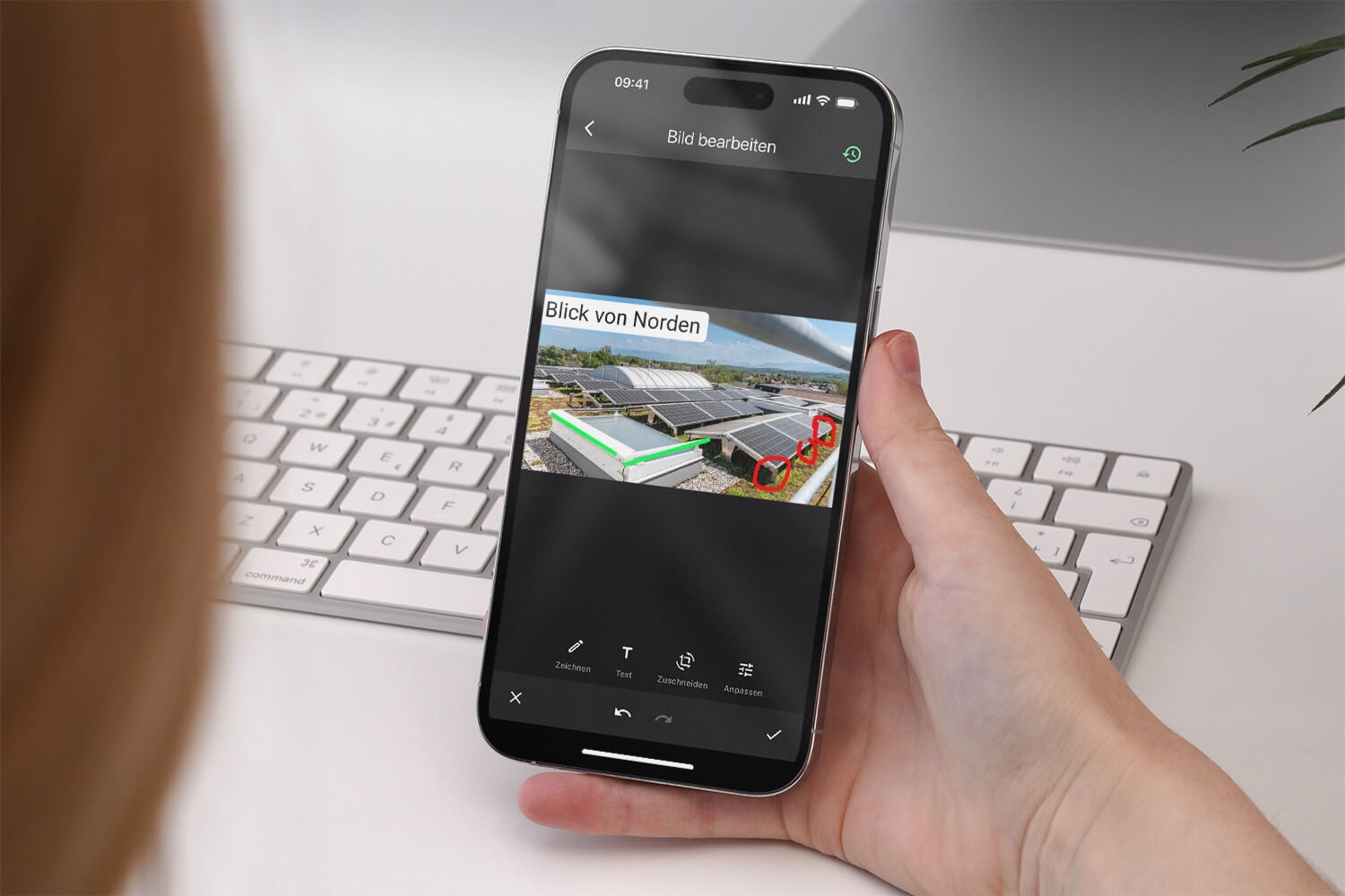 Hand hält ein Smartphone mit dem Bildbearbeiten-Bildschirm der Offpaper App: Auf dem Foto einer PV-Anlage sind ein Textfeld und farbige Markierungen eingefügt, unten die Werkzeuge Zeichnen, Text, Zuschneiden und Anpassen